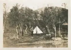 Fem mennesker står rundt et telt, teltet er slått opp ved et