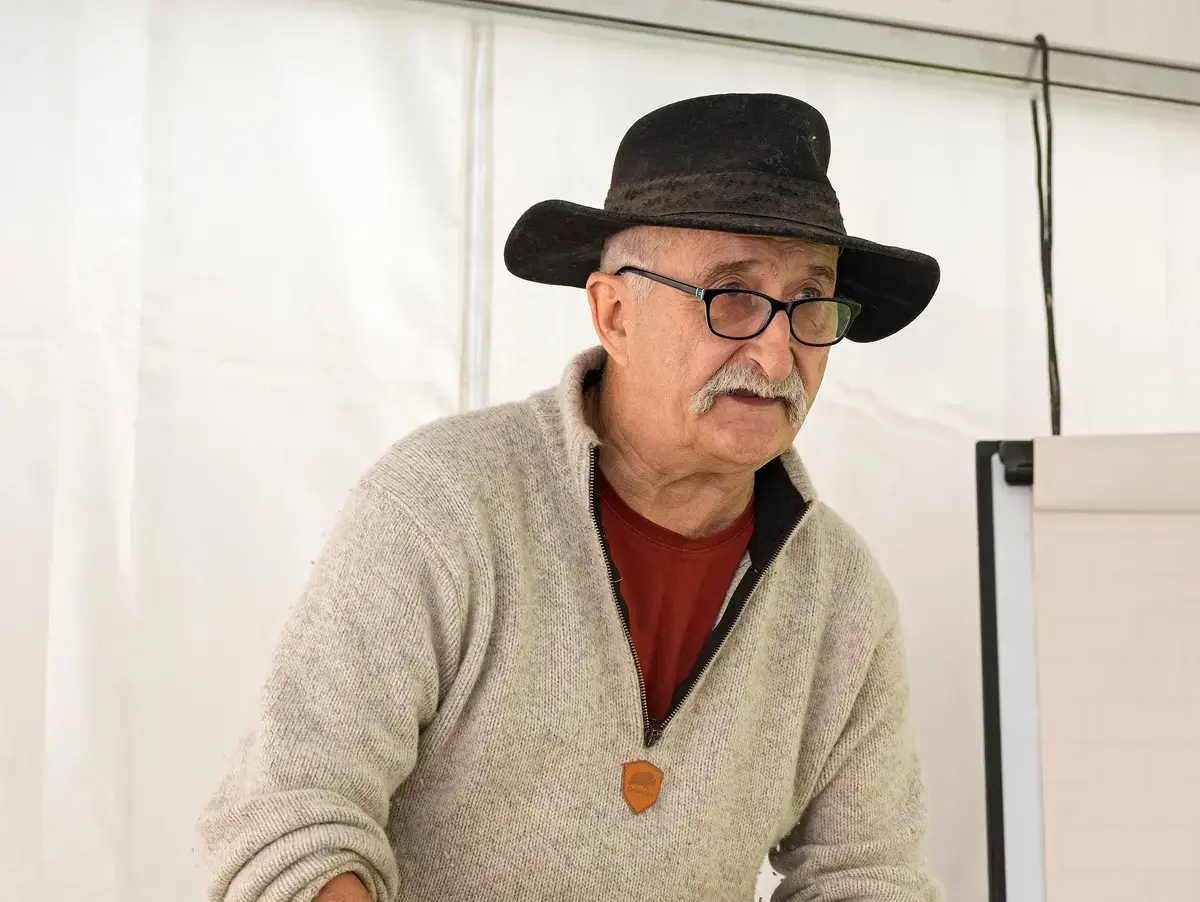 Mann med hatt og ullgenser sliper kniv 