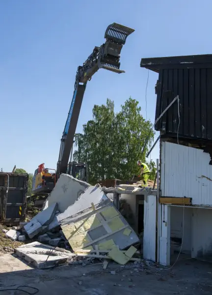 En gravemaskin med åpen klo på heist gravearm står klar til å ta en "jafs" av det gamle restaurantbygget på Domkirkeodden.