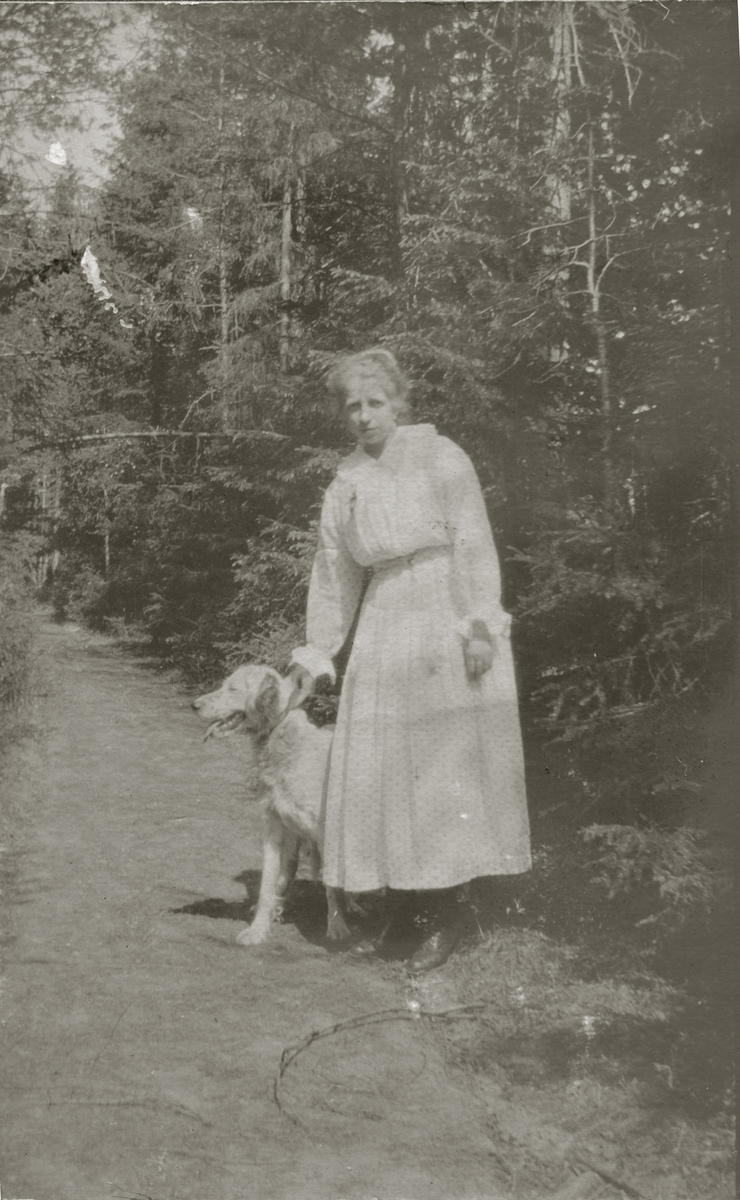 Ung kvinne i lys sommerkjole med hund.