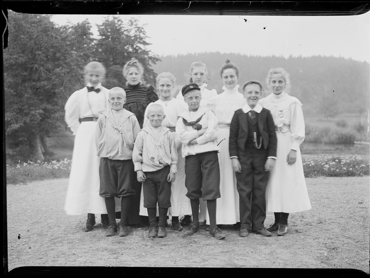 Et gruppebilde av ti barn; gutter og jenter. I bakerste rad estår Minnie Christensen (3. fra venstre), Anna og Eva Christensen (lengst til høyre).