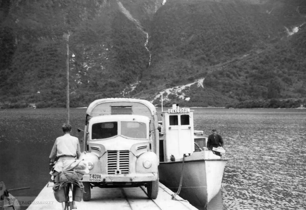 Lastebilen er en Dodge godsvogn med reg nr T-8208 og tilhørte Eira Auto..Dett er en engelskbygd Dodge, også kalt Dodge Kew. Modellen var ny i 1949 og ble importert i et visst antall, bl.a. som følge av at Norge manglet amerikanske dollar i perioden...Eira Auto drev ruter med busser og godsvogner Eikesdalsvatn-Eidsvåg-Molde. Fram til 1963 var det båtrute på Eikesdalsvatnet som fraktet varer og passasjerer. Omlasting av varer fra bil til båt skjedde på Øverås ved Eikesdalsvatnet. I 1963 ble det satt inn bilferje på Eikesdalsvatnet, og godsbilen kunne nå følge ferja til og fra Eikesdalen. T-8208 var en Dodge Kew 1950-modell som gikk i denne godsruta i ni år til 1959.