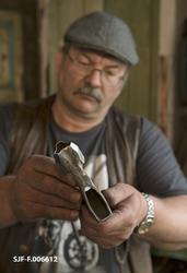 Willy Bruun studerer og viser fram ei merkeøks som smeden Od