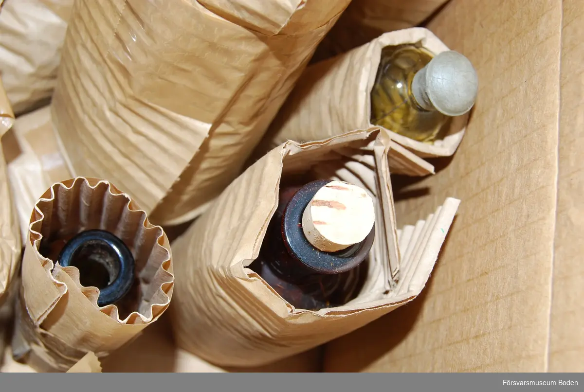 Kartong innehållande olika flaskor, emaljerade kärl samt suturtråd i flaska.