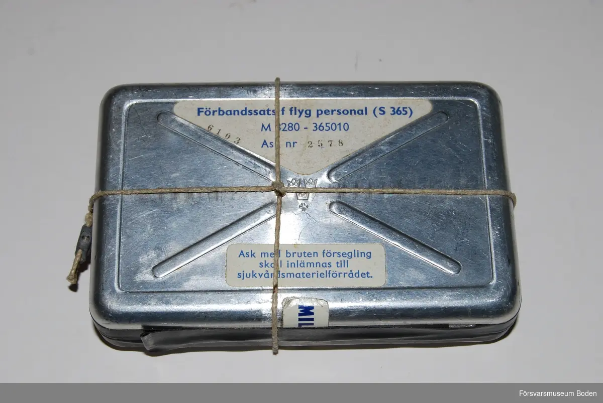 Plomberad aluminiumdosa 7,5 x 12 cm. Bör innehålla förbandspaket för bränn- och sårskador. Materielnummer M8280-365010.