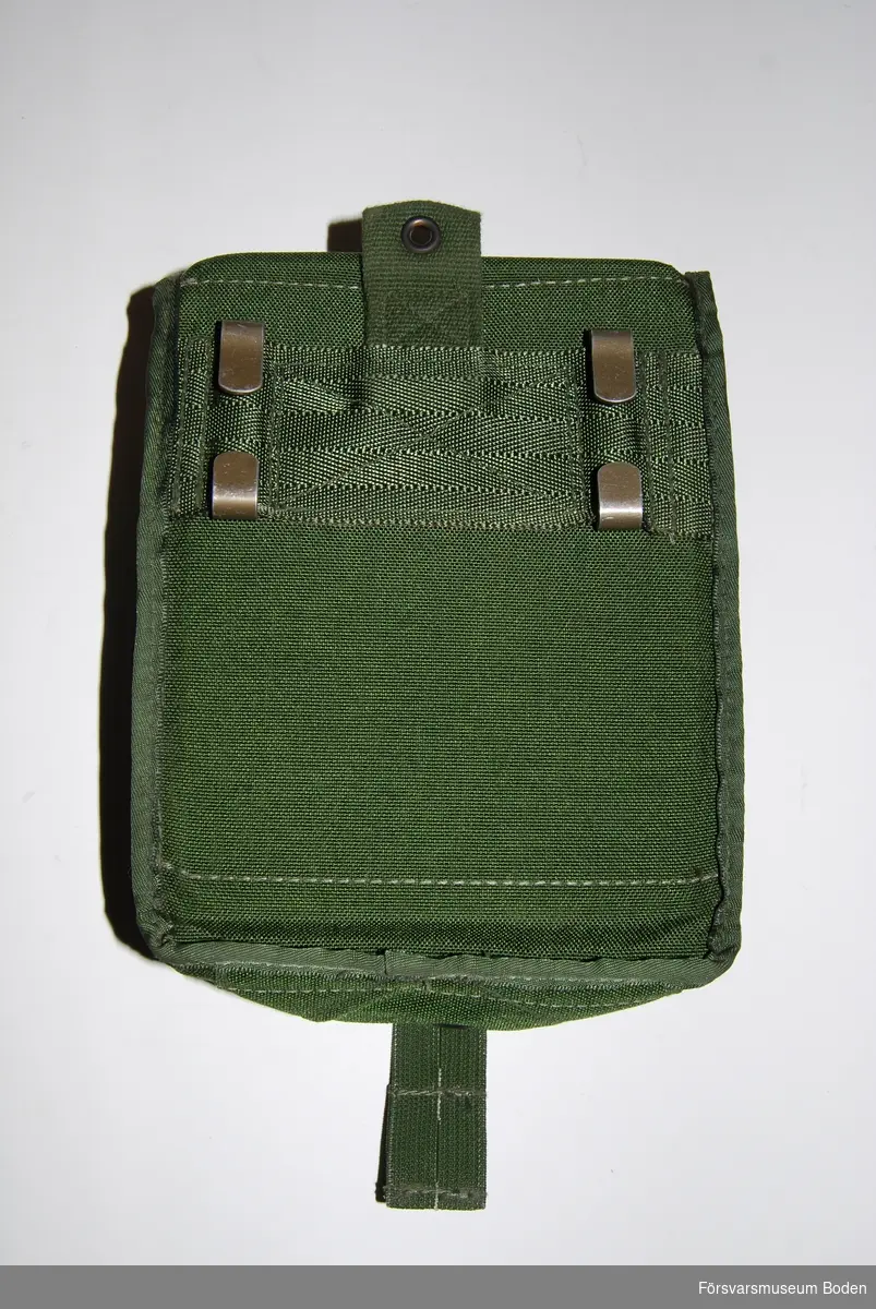 Av grönt syntettyg med metallhakar för bältet på baksidan. Lockets slejf har två valfria knapphål. Avsedd för fyra st AK47-magasin eller fem M16/M4-magasin.