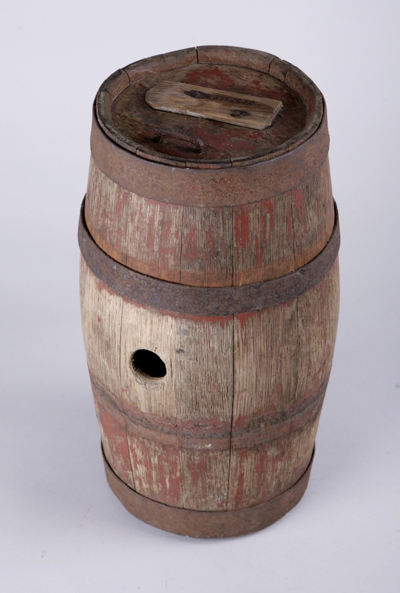 Sylinderformet tønne med tre jernbånd (mangler ett), rund bunn og topp. Et rundt hull midt på.