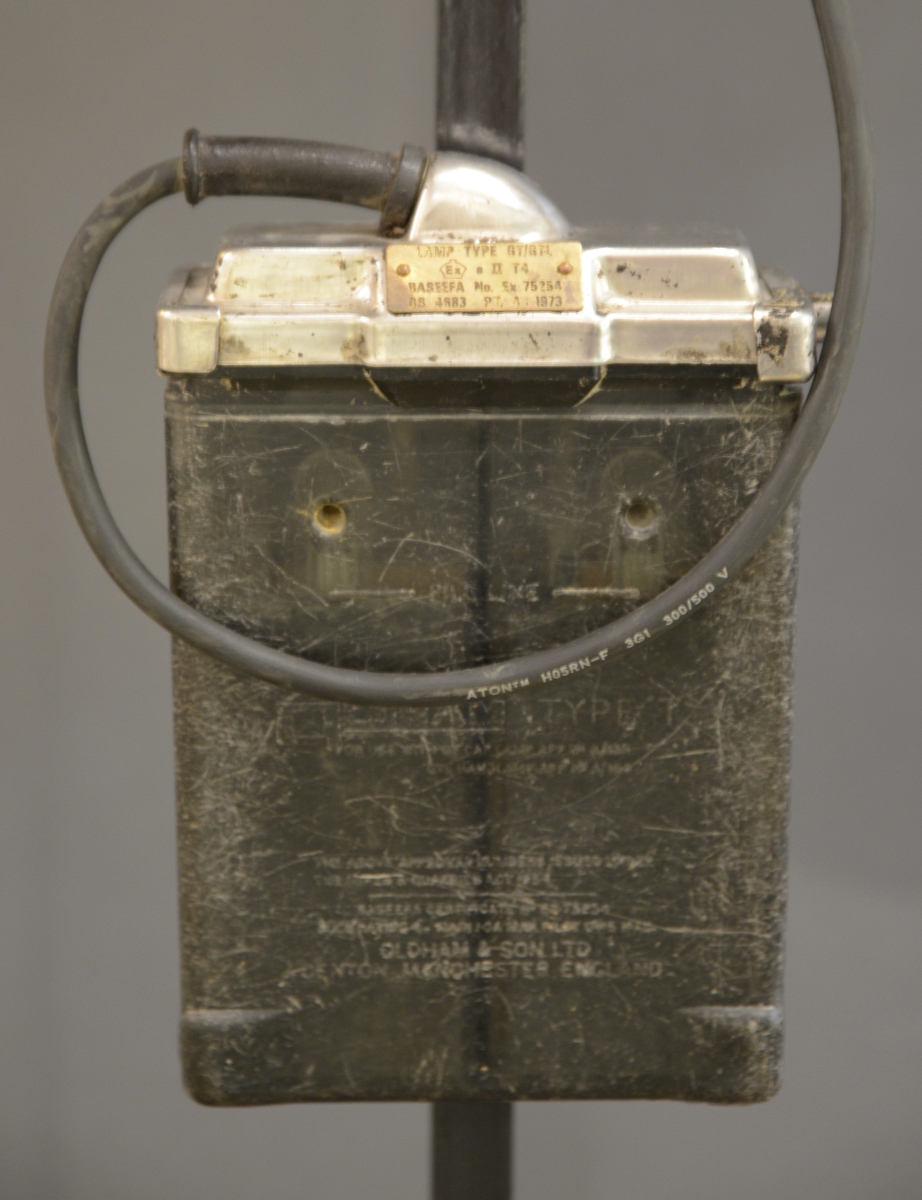 Rektangulært batteri koblet til rund lampe som kan festes på vernehjelm.
