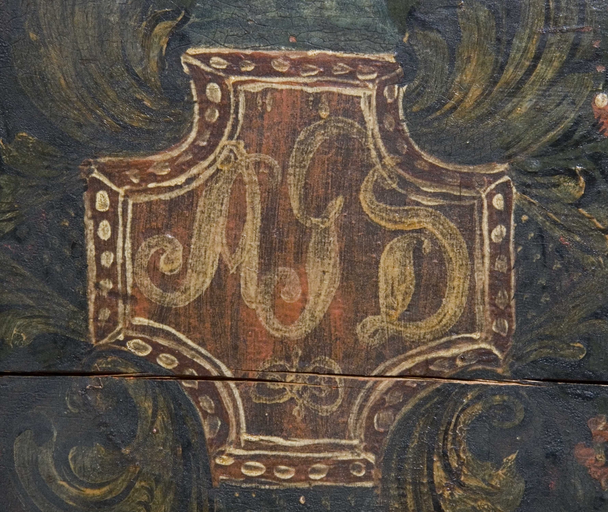 Kiste med buet lokk og heldekkende rosemaling, hvorav mye er senere tilføyelser eller restaureringer. Kulebena er også sekundære.