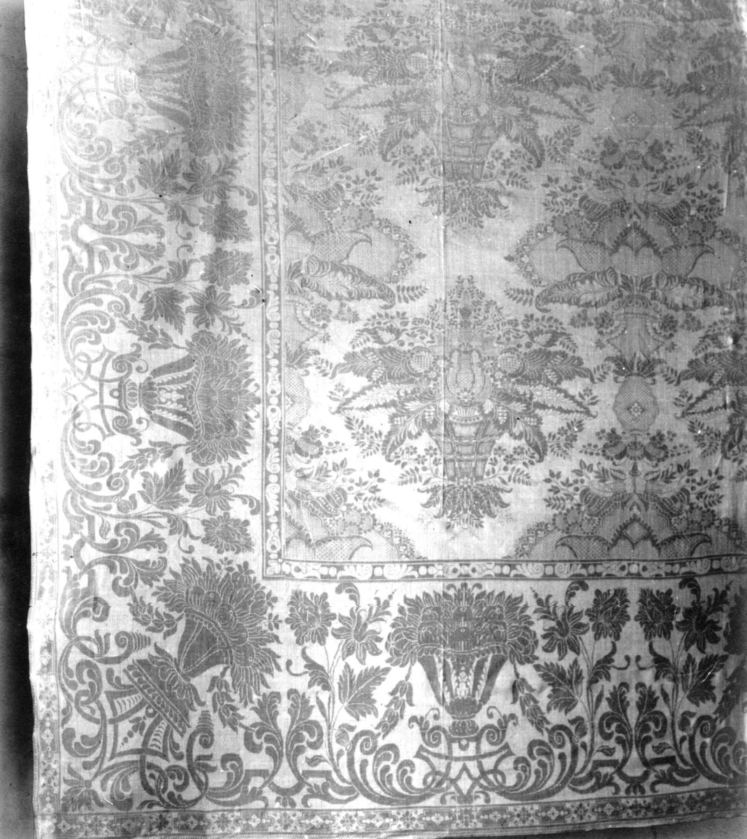 Hvit damaskduk med mønster av store blomsterklaser. Antagelig fra Sachsen Tyskland 1749.