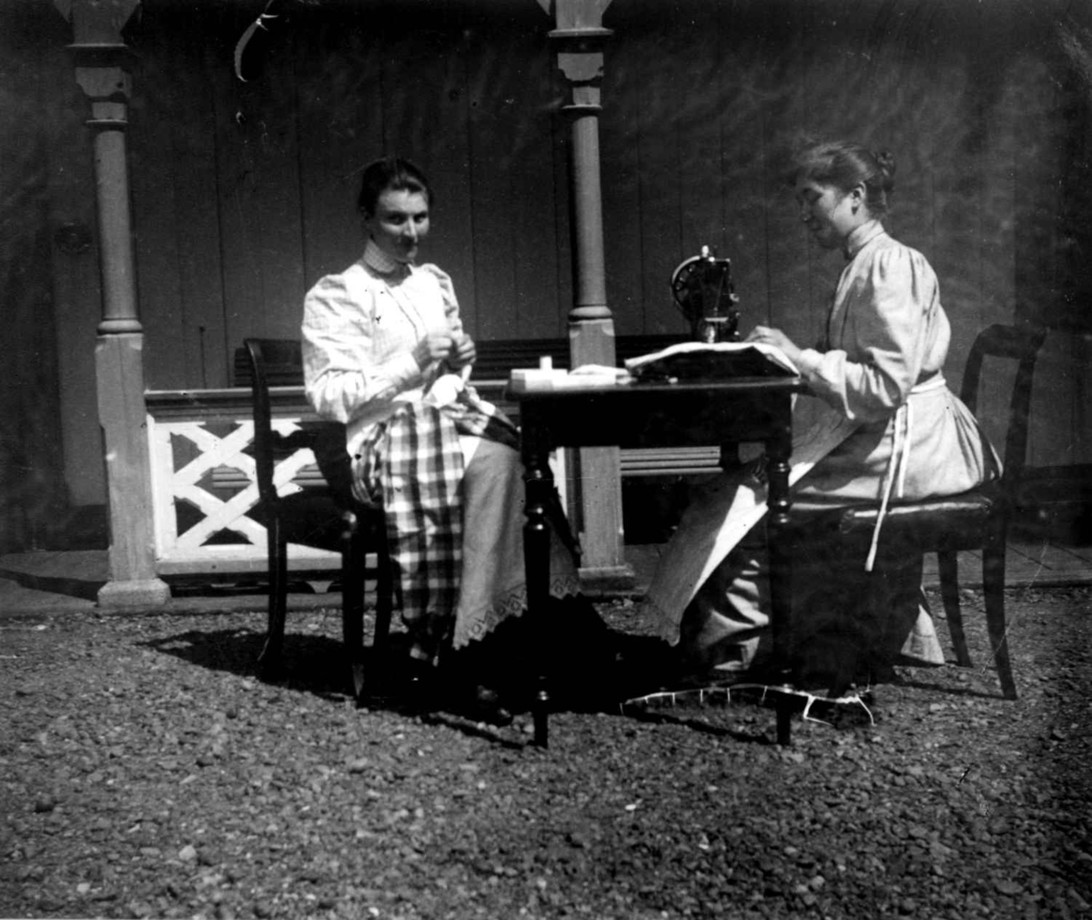 Sypiker, Dal gård, Ullensaker, ca. 1893. To kvinner med søm utendørs, den ene på symaskin.
Fra portrettserie av personer som bodde på eller besøkte Dal gård, Ullensaker, fotografert av gårdens eier, kammerherre Fredrik Emil Faye (1844-1903) i årene 1875-1900.