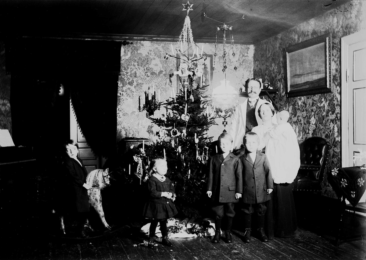 Familie feirer jul med juletre og gyngehest. Interiør, ant. fra Nedre Digerud, Frogn, Akershus, hos familien Quinsgaard Wiborg.