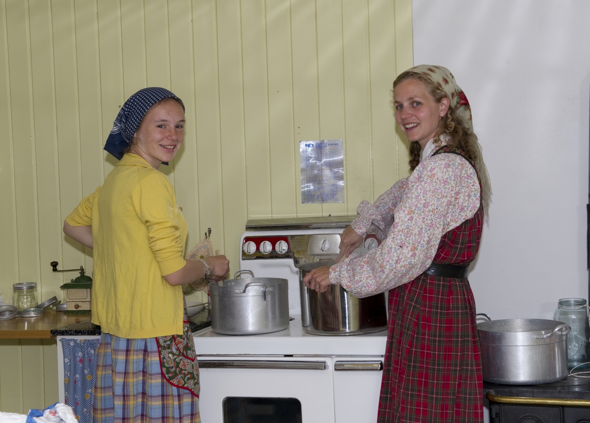 To jenter lager mat på kjøkkenet. Trønderskolen anno 1959. Norsk Folkemuseums sommertilbud til ungdom. Deltakerne prøver seg på praktiske arbeidsoppgaver som det var vanlig at ungdom deltok på for 50 år siden. Trøndelagstunet på Norsk Folkemuseum, 1. august 2012.