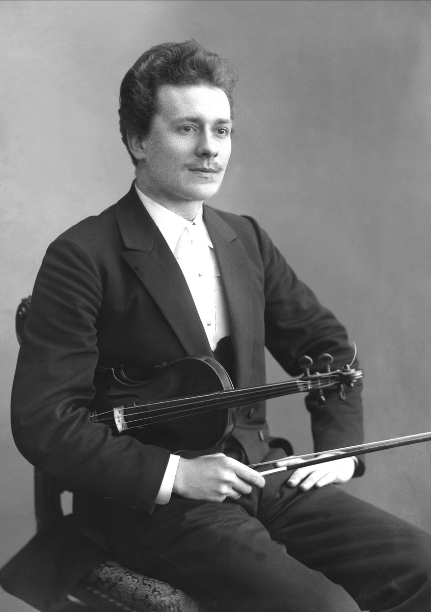 Portrett, sittende mann med fiolin under armen. Frantz J Furicek.