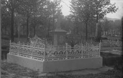 Gravsted, steinstøtte på opphøyd platting med smijernsgjerde