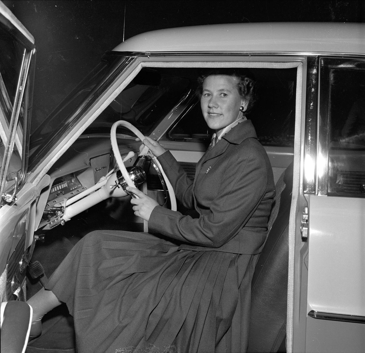 Bilutstilling, merke Ford, antakelig Oslo, 10.09.1956. Dame i førersete på bil.