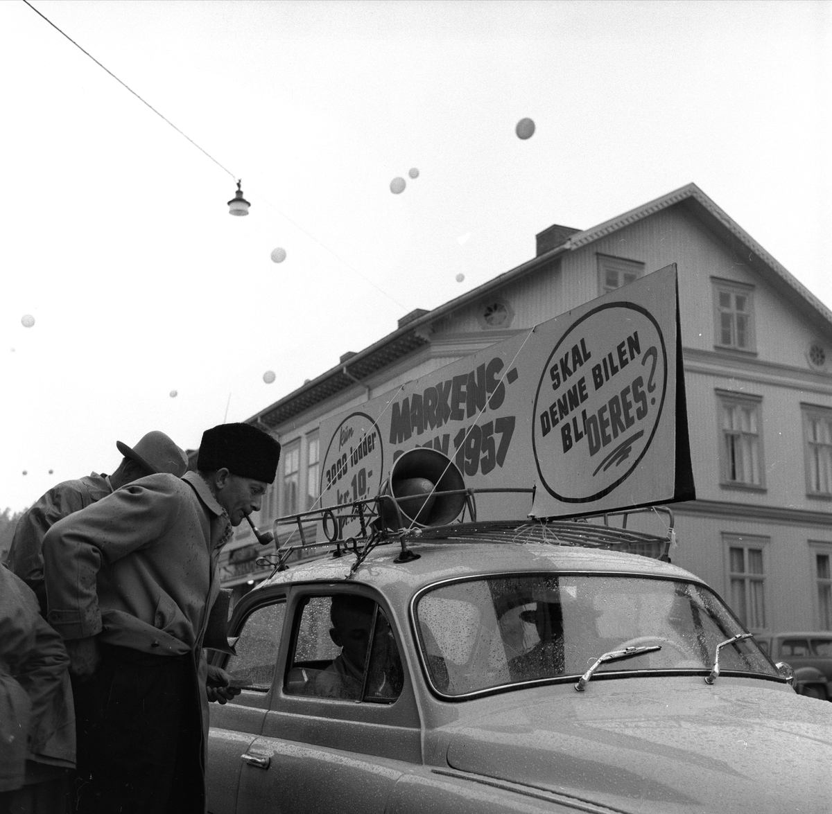 Gjøvik-Marken, Gjøvik, Oppland, 24.10.1957. Reklame for bilsalg, bil og folk i gata.