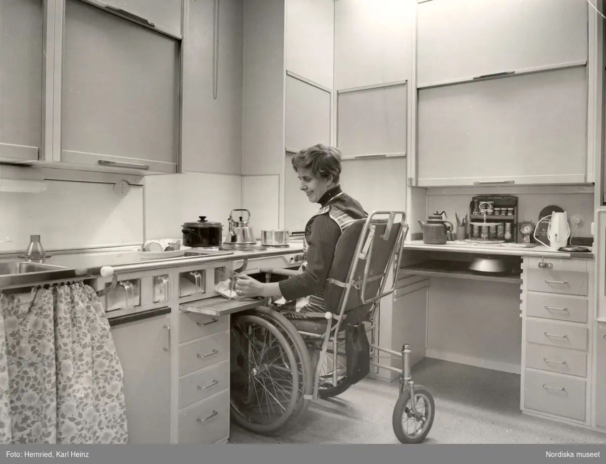 Handikappanpassat kök. Kvinna i rullstol vid spis