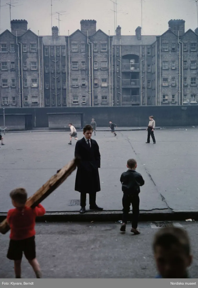 Barn som leker på en asfalterad plan. Bostadshus, höghus, i bakgrunden. Irland.