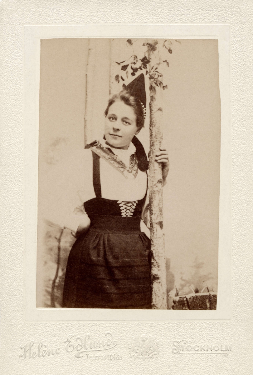 En kvinna poserar i folkdräkt från Rättviks socken i Dalarna. Ateljéporträtt.