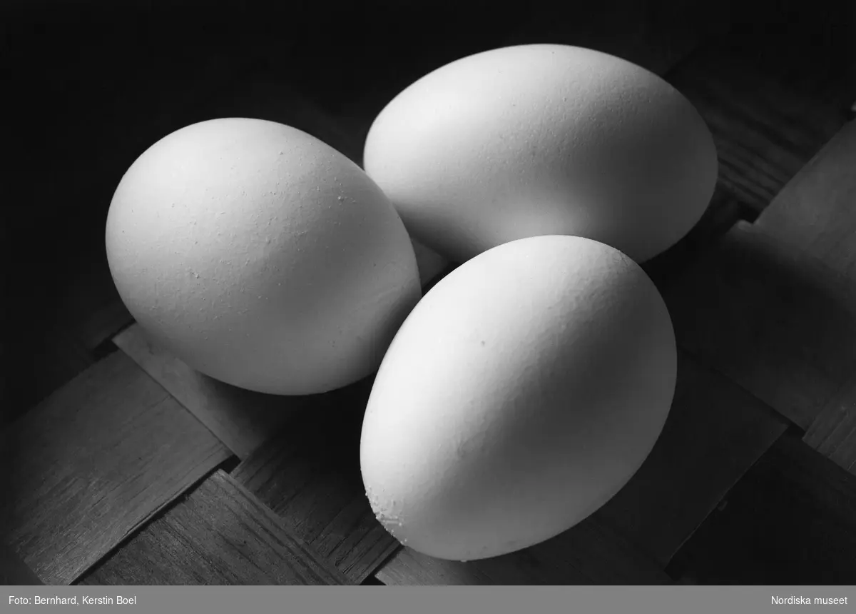 Ägg. Tre stycken ägg på ett flätat underlag.