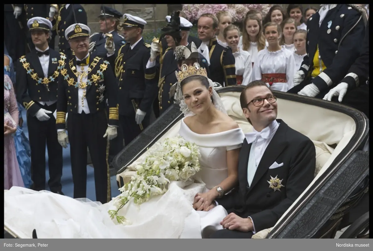 Kronprinsessbröllopet den 19 juni 2010. Kronprinsessan Victoria och prins Daniel i vagn inför sin kortegerunda genom Stockholm. I bakgrunden H.M. kung Carl XVI Gustaf och prins Carl Philp.