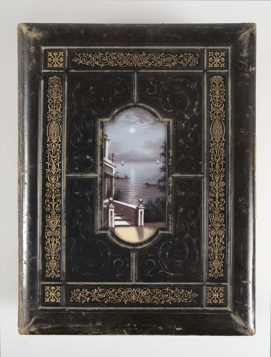 Fotoalbum med pärmar av svart läder och dekor i relief och guldtryck. På framsidans pärm finns en mittspegel av glas på vilket ett landskapsmotiv i månsken är målat. På baksidans pärm finns fyra nitar av metall.