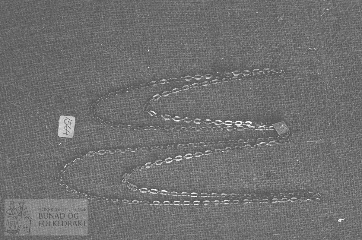 Dameklokketrosse med sirupsnippformet glider. Gravert ornament på oversiden. "Glideren": 20mm x 12,5mm. Ingen stempel.