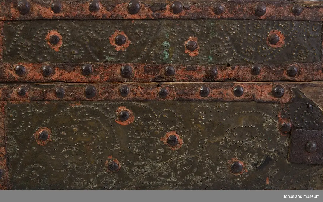 Kassaskrin av trä, nästan fyrkantigt, med platt lock, metallbeslaget.
Tillverkat under 1600-talet. Skrinet har tillhört Gesäters kyrka i Dalsland och primärt använts som kyrkokassaskrin.

Metalldelarna är av olika slag. Mässingsplåt täcker skrinets hela utsida, förutom undersidan. Mässingsplåten är punsdekorerad och hålls på plats av fastnitade dekorband av järn. Järnband och nithuvuden är en del i mönstereffekten. Spår av röd färg finns på järnbanden.
Nitar, nithuvuden och lockets handtag saknas. 
Inuti locket står årtalet "1786" i vitt samt "Hilma Carolina 1880" skrivet i blyerts. Kistebrev har funnits inuti locket.
Nedre delen har varit uppdelad i nio fack.
Nyckelskylt saknas. Gångjärnen är sekundärt skruvade.
Plåten är defekt.

Se Knut Adrian Andersons "Katalog I, A. yngre föremål", under Uddevalla museum/förening D 2A:1 i arkivet.

Ur handskrivna katalogen 1957-1958:
Kyrkokassa-skrin
Bottenmått: 24,5 x 25,5. H: 14,5. Träskrin med plåt- och järnbeslag. Skadad bl. a. saknas lås. Maskhål. Gesäters k:a, Dalsland 18