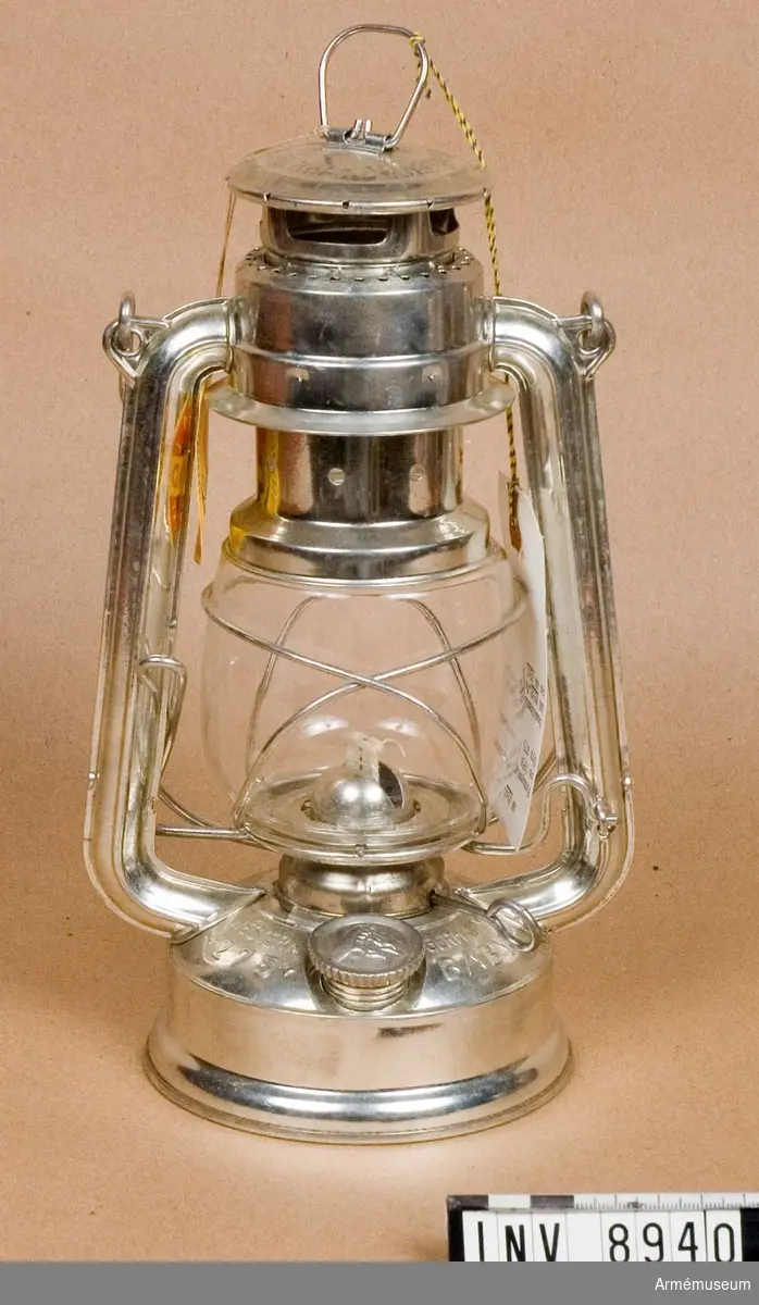 Bärbar.Typ 275 (Baby). Märkt Orginal-Nier-Patent. Feuerhand (Westen Germany). Fotogenlyktan består av en ringformig fotogenbehållare med lampglas runt omkring brännaren.

Samhörande nr är AM.8939 - 8941
