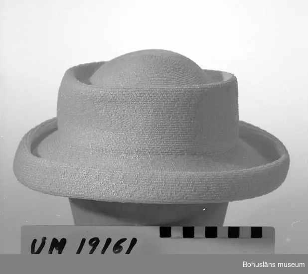 471 Tillverkningstid 1950-TAL
410 Mått/Vikt !H.6,5 BRÄTTB.5 CM
394 Landskap BOHUSLÄN

Hatt i ihop sydd syntetfläta. Vit färg. Modell med kort invikt brätte. Platt kulle.