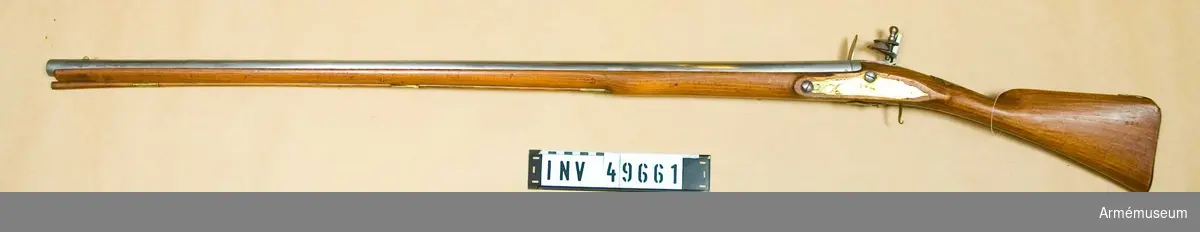 Grupp E XIV.
Loppets relativa längd är 53 kal. Afrikanskt gevär med flintlås. Sidblecket består av en  mässingsskiva med gravyr föreställande båge med koger och  pilar. Varbygeln fattas. Barker.