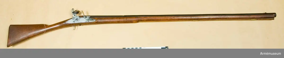 Grupp E XIV.
Loppets relativa längd 56,2 kal. Afrikanskt gevär med flintlås. Varbygeln fattas. På pipan och kolven finns siffrorna 233.