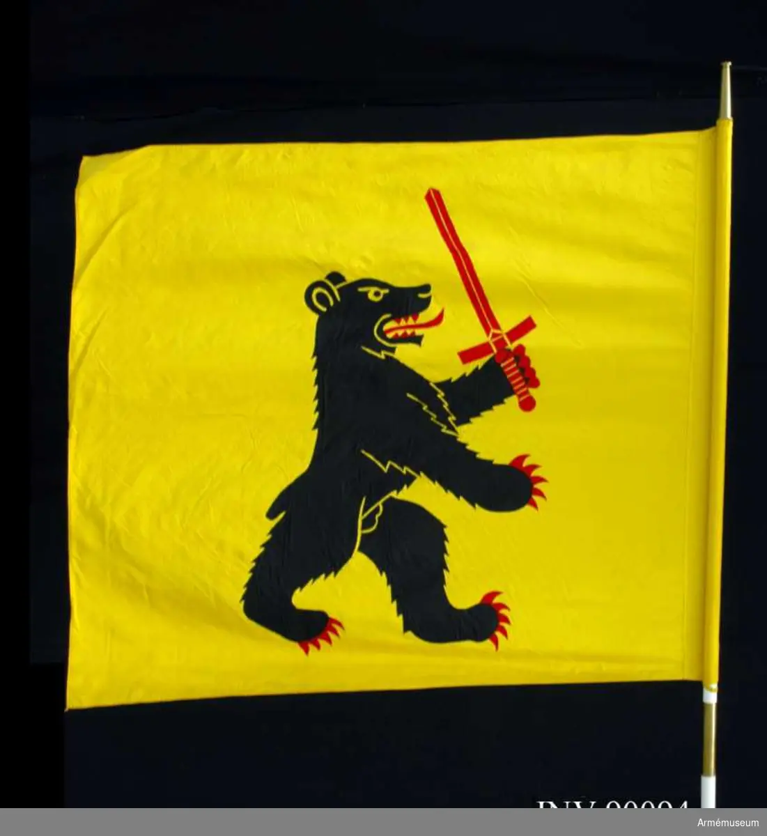 På gul duk förbandets vapenbild: en upprest svart björn med röd beväring och med ett rött svärd i högra framramen.

Fanan är utförd i textil intarsia med maskinbroderade detaljer. Duken är av natursiden. Vitmålad, tvådelad stång med doppsko och holk av förgylld mässing.  På doppskon är ingraverat: "Kalix försvarsområde Fo 67"