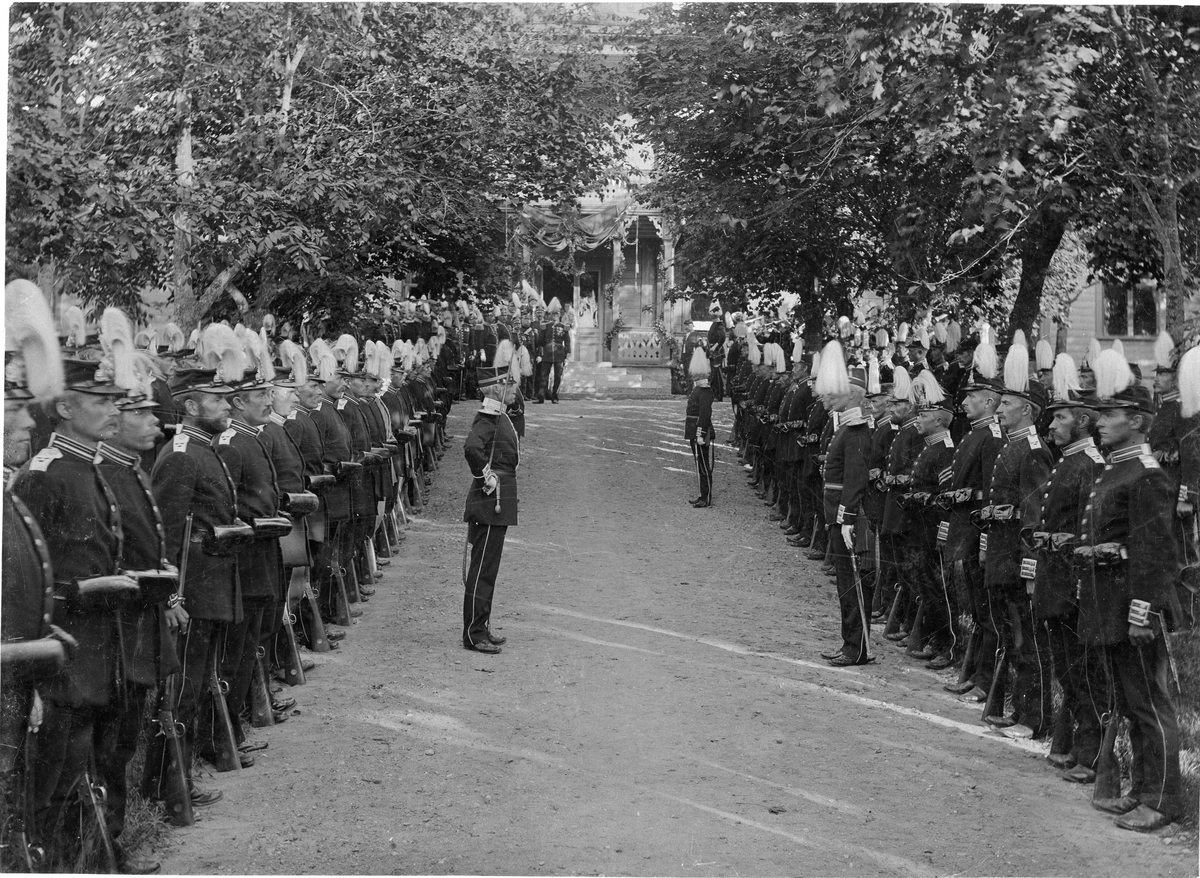 Livkompaniet vid Livregementet till fot (I 3) paraderar vid ingången till officerarnas matpaviljong den 29/8 1897, då officerskåren gav middag för sin avgående chef, överste Johan Lilliehöök. I bakgrunden spelar musikkåren.