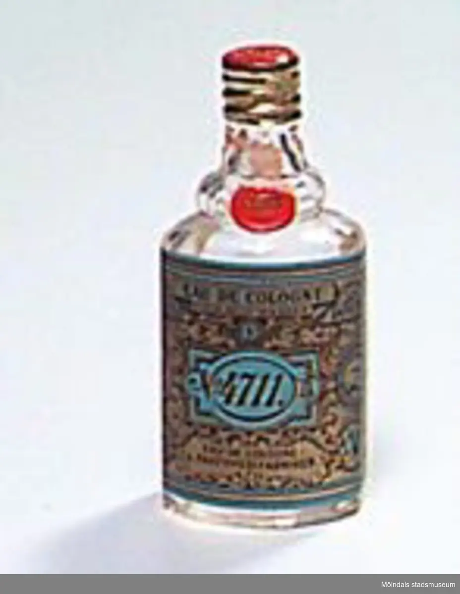 En liten genomskinlig parfymflaska med Eau de Cologne 4711 i glas med en pappersetikett som är rikt dekorerad i guldfärg, svart och blått. Innehåll finns kvar i flaskan. Röd och guldfärgad metallkork.
Det var troligtvis en italienare, Giovanni Feminis från Milano, som i slutet av 1600-talet startade tillverkningen av parfymer i Köln. Namnet 4711 står helt enkelt för numret på huset där parfymen tillverkades. I Tyskland används denna parfym fortfarande mycket. I Sverige köps ca 50.000 stycken 100-millilitersflaskor om året, lite jämfört med förr, och mest av äldre människor. Parfymen säljs fortfarande ifrån Köln.