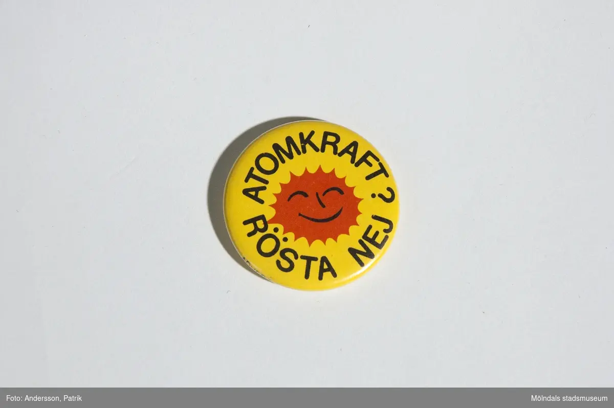 Pinn med symbolen och texten: "ATOMKRAFT? RÖSTA NEJ".Den har gul bakgrund, symbolen är röd och texten är svart.Denna användes av Lena Måvholm 1979 i samband med  folkomröstningen om kärnkraft i Sverige som skedde 1980.MåttDiam: ca. 38 mm1980 skedde en folkomröstning om kärnkraften i Sverige. Då var det många personersom under 1970 och 80-talet bar på denna symbol. Antikärnkraftsymbolen liknade ett glatt rött/orange eldklot och hade texten: â€ATOMKRAFT? NEJ TACKâ€. Det var en livskraftig symbol som ville visa energi och framtidstro. Den ville visa vad man borde använt sig av i stället såsom solen, naturen och vinden.