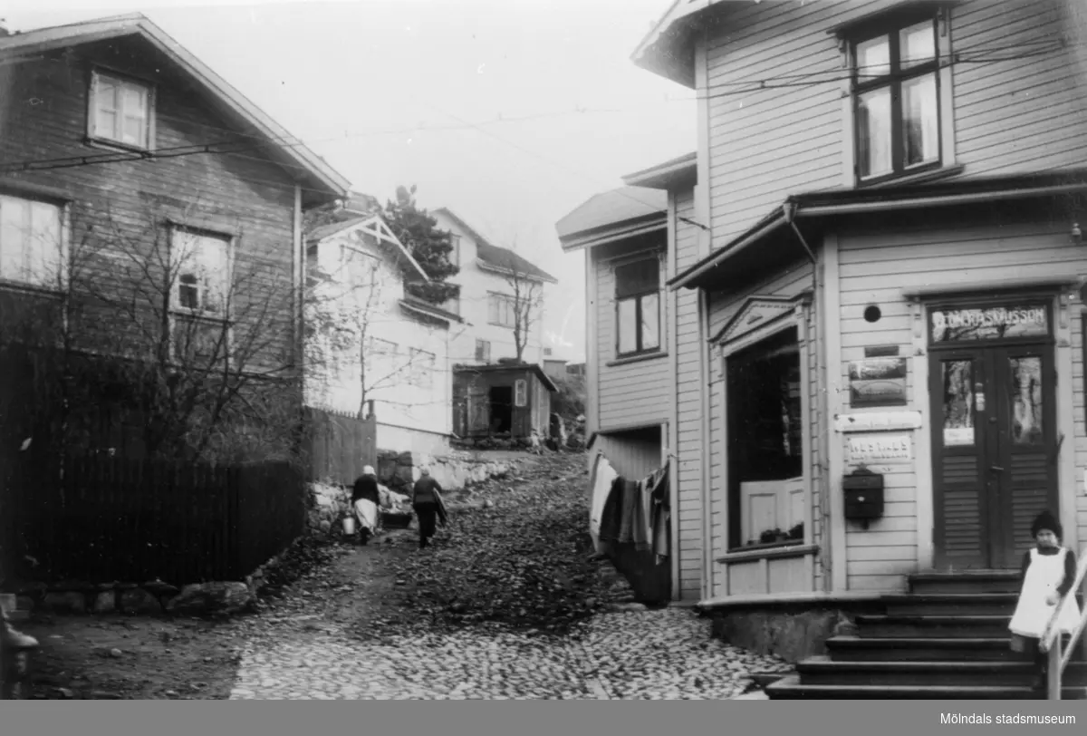 Lundsstigens (nuvarande Millbergsstigen) mynning på Forsåkersgatan, år 1921. Till höger Leon Rasmussons filialaffär (senare "Majkvists") vilken nu är riven.