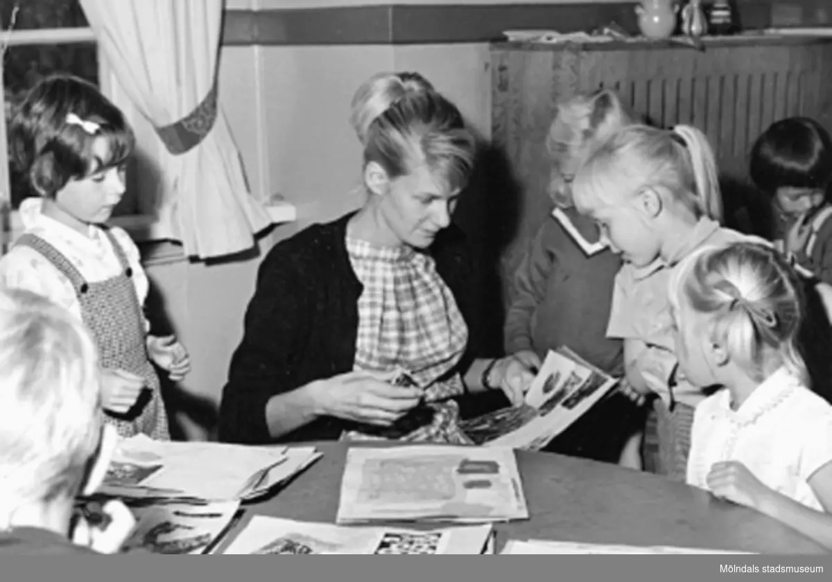 En lärarinna och några barn pysslar vid ett bord. Holtermanska daghemmet 1953.
