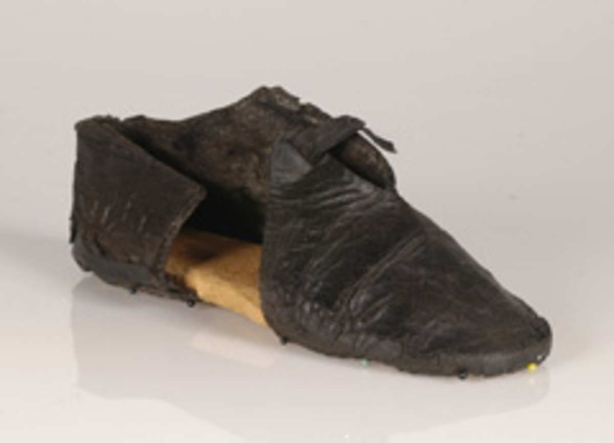 Monterad sko i form av en skoöverdel, troligtvis till en vändsydd barnsko. Med stor sannolikhet daterar sig skon till tiden före förlisningen 1628, eventuellt 1500-tal.
Skons överdel är skuren i ett stycke. Skoöverdelen har, med hjälp av en rektangulär skarvbit omslutit hela foten. Skarvbiten, som nu saknas, har suttit fästad på sidan av skon. På skons ovansidan, mot vristen, finns en något triangelformad, spetsig öppning. Över öppningen löper det en smal rem. Remmen har suttit fästad på det nu saknade sidostycket. Remmen har förts genom en skåra lädret, vikts över vristen och sedan fästs i skåror i lädret på skons motsatta sidan. Skobottnen saknas. Skoöverdelen sitter fästad på en träbotten och överdelens nedre kanter har förstärkts emd svart kartong av konserveringsenheten.
Lädret tycks vara relativt välbevarat.