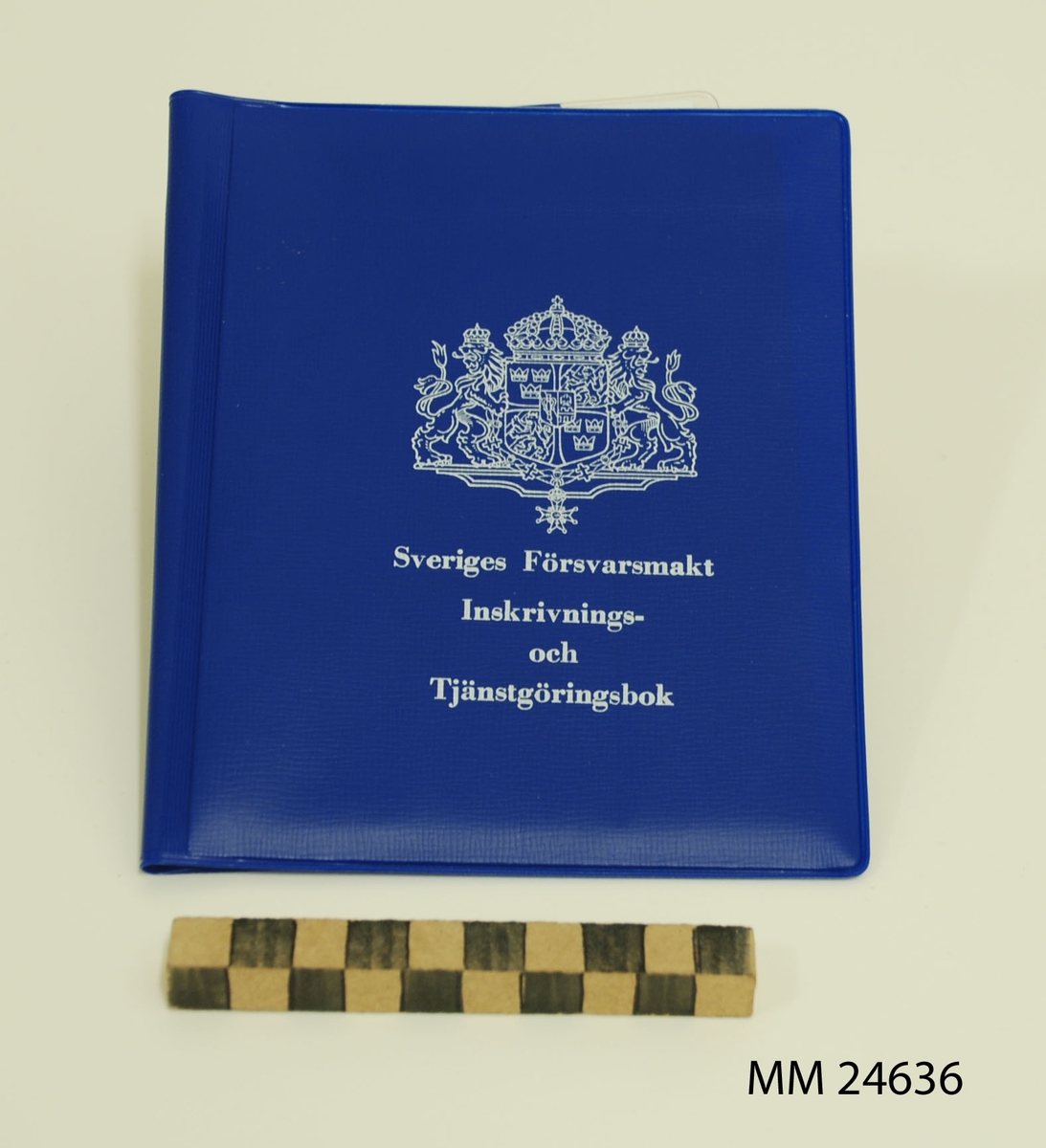 Inskrivnings- och tjänstgöringsbok. Fodral av blå plast med vit tryckt text: "Sveriges Försvarsmakt Inskrivnings- och Tjänstgöringsbok" samt stora riksvapnet.  På baksidan tryckt text i vitt: "M7102-383430-9. Utgåva 3. (VPV). 75-05. 50 000 ex. LF-ALLF 405 75 231". Plastfickor på fodralets insida. På ena sidan finns terminslönekort. På andra sidan finns tjänstgöringskort, krigsplaceringsorder, en folder kallad "Minneslista" samt en identitetsbricka av plåt. Foldern "Minneslista" innehåller ett sammandrag av de viktigaste bestämmelserna som värnpliktiga behöver känna till. Foldern giltig efter 1971.