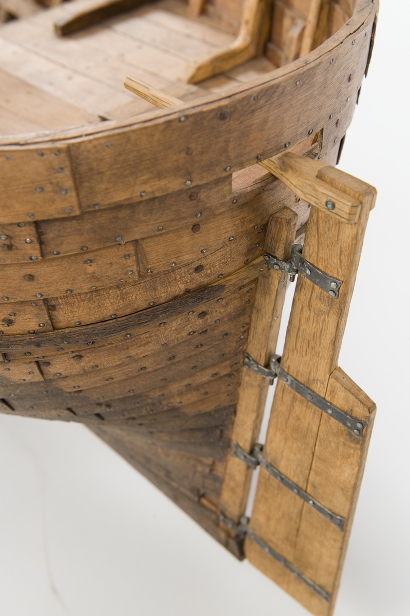 Fartygsmodell. Lastskuta från 1500-talet, klinkbyggd med sjutton bord på var sida, odäckad med back och akterdäck. Skrovet betsat ljust och mörkt. Pump och roder, röstjärn av trä, ankare och riggad mast.