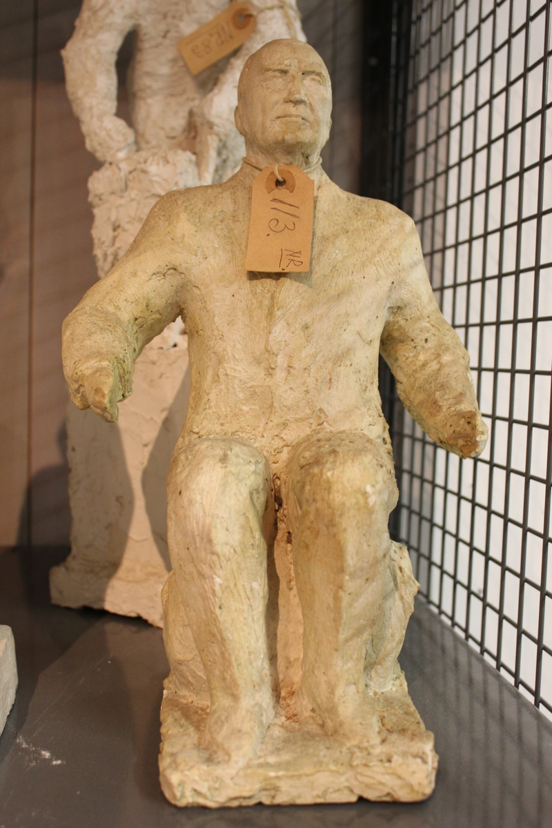 Skulptur i gips av en sittende mann.