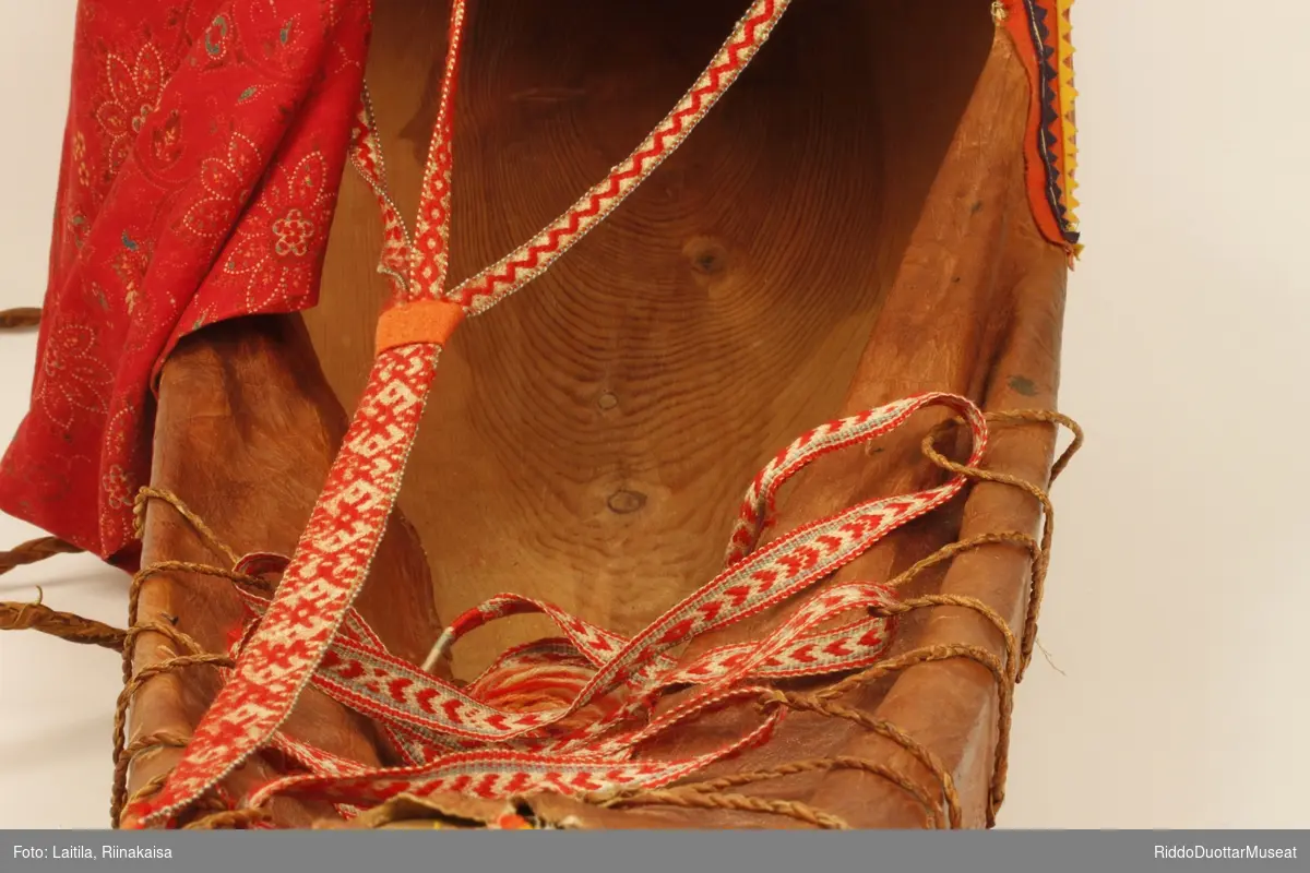Komsen består av et skjelett av tre trukket med skinn, og pyntet med vevde bånd i flere farger.