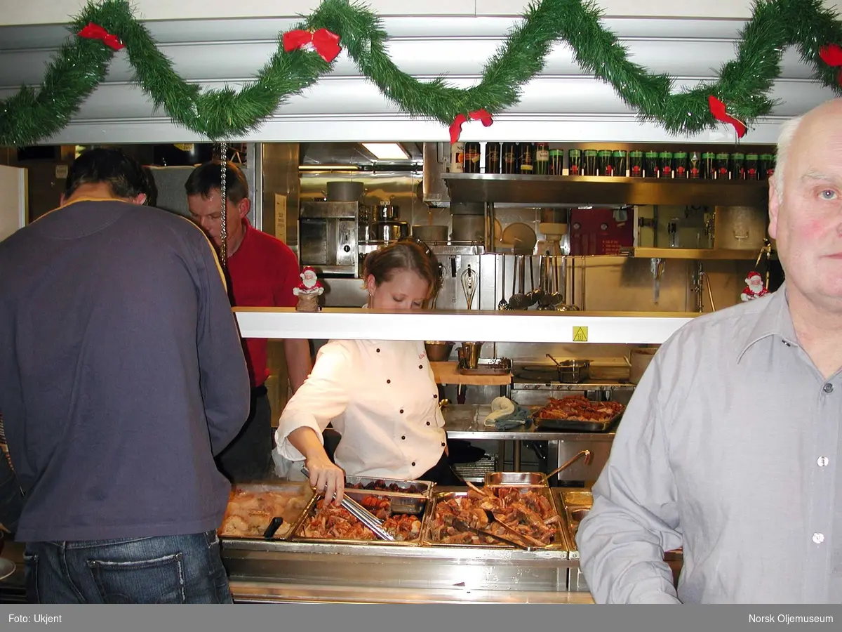 Julefeiring i messa på QP i 2004.  Serveringspersonalet står bak disken og sørger for at maten til enhver tid er innbydende og klar for servering.   