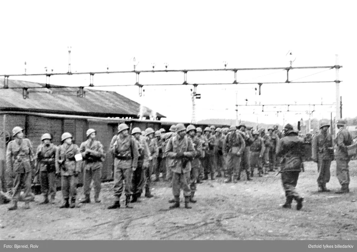 Da freden "brøt løs" i maidagene 1945. 
Soldater marsjerer ved jernbanestasjon. Reservepolitiet hjem fra Sverige.