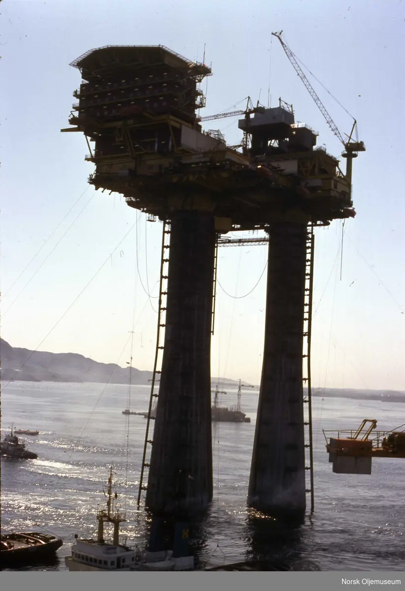 Brent D ved byggeplassen i Gandsfjorden.  Statfjord A er under bygging og skimtes bak plattformbeina.