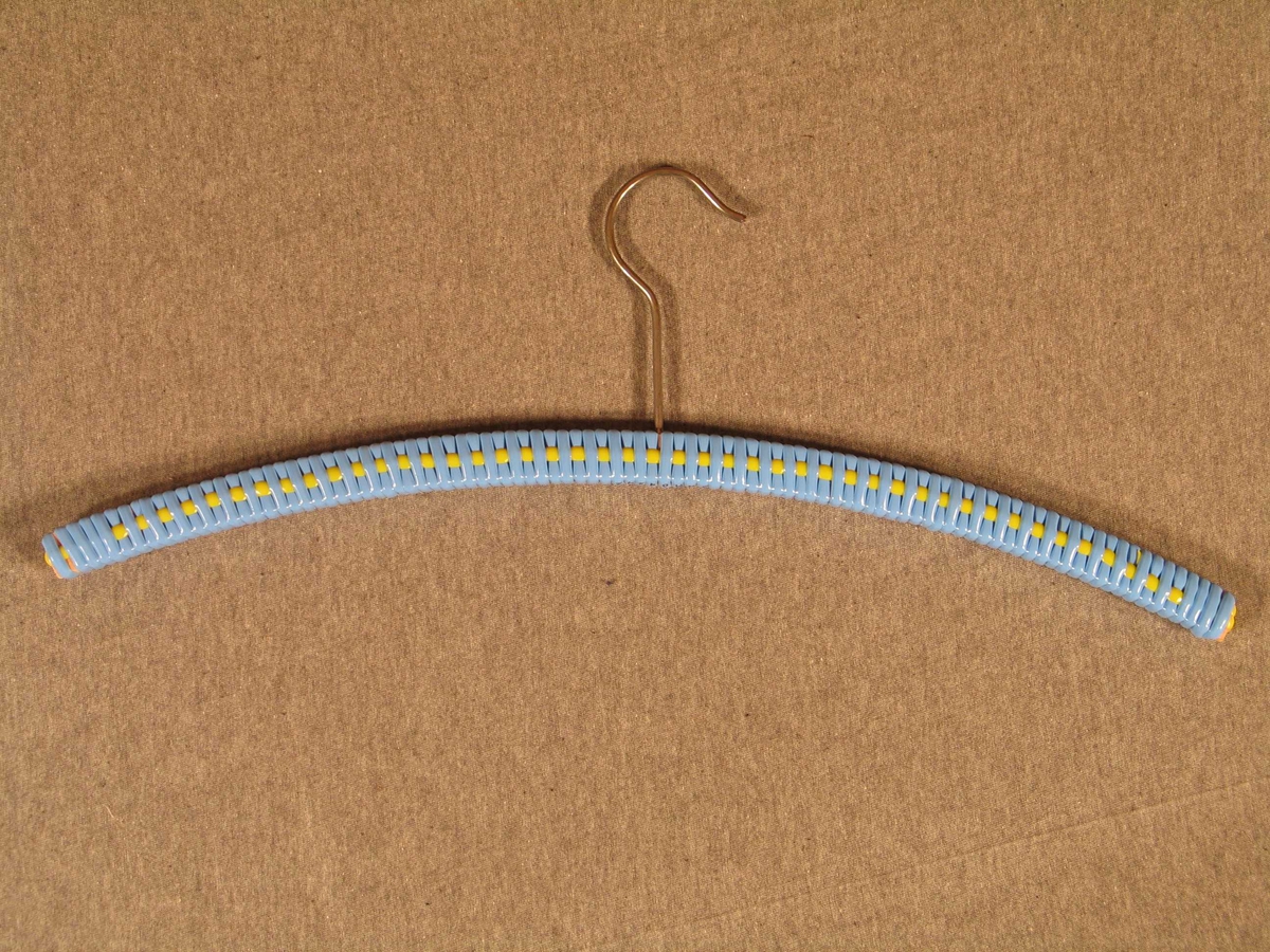 Trebøyle med stor metallkrok midt oppå for opphenging på stang. Bøylen er kledd med blått plastband, inn i dette er fletta eit tversgåande band i gul plast.