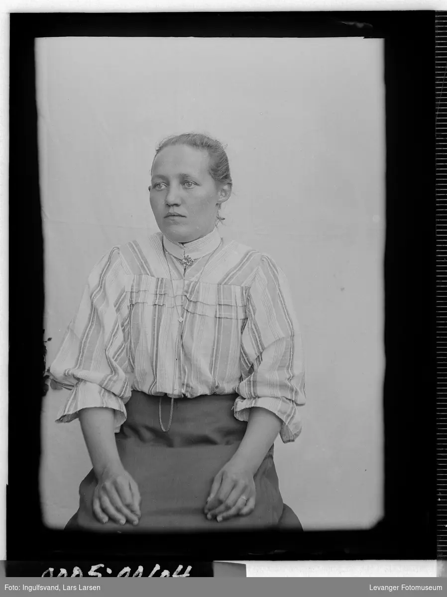 Portrett av kvinne i halvfigur iført bluse og skjørt med klokkekjede.
