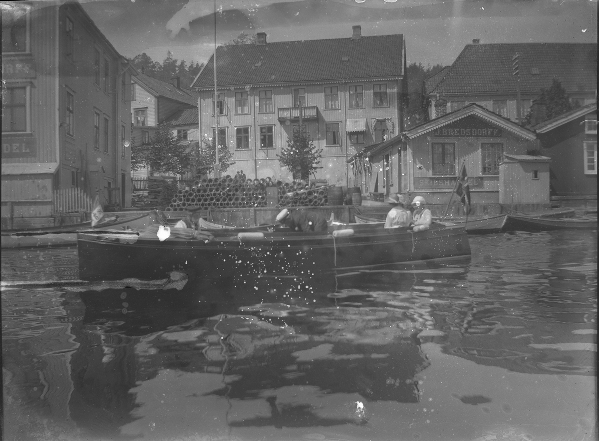 Person i båt i Blindtarmen, utenfor Bredsdorffs Skibshandel. Kragerø